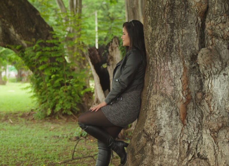 devojka naslonjena na zid u sivoj haljini, crnim čizmama i hulahopkama