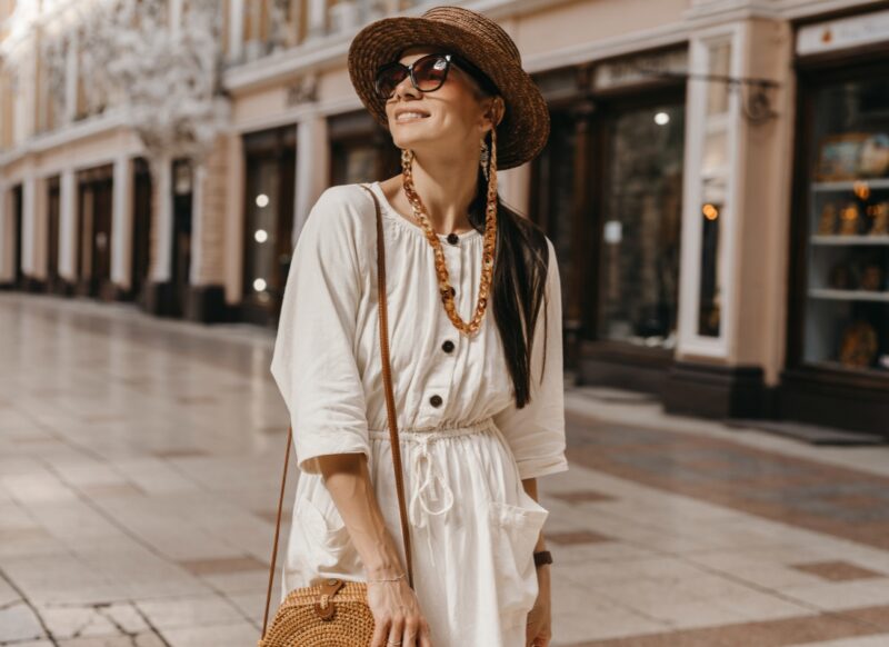 devojka na ulici u beloj haljini, sa naočarama šeta u boho stilu
